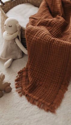 a stuffed animal sitting on top of a bed next to a blanket and teddy bear