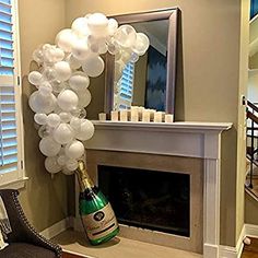 the balloon arch is decorated with white balloons and a bottle of champagne in front of a fireplace