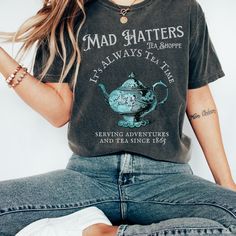 Get ready to be OBSESSED with your new Alice in Wonderland Lewis Carroll Mad Hatter shirt. It's the cutest and most trendy way to combine all those important trendy dark academia and literature shirt vibes! This is the perfect disneyworld shirt!  * Q U I C K * F A C T S * ✺  All shirts are UNISEX ✺  100%  ringspun cotton (fiber content may vary for different colors) ✺  Soft-washed, garment-dyed fabric brings extra coziness ✺  Wash and dry normally (on cool for best results) ✺  Sewn-in twill label * S I Z I N G * ✺ For an oversized fit, select two or three sizes up from your normal size ✺ Model is wearing size L  ✺ Sizing runs true to size ✺ Relaxed fit ✺ Most women find their typical size works best, since they are meant to fit a touch loose ✺ See Size guide and fit in images          * S Tea Shirts For Women, We're All Mad Here Shirt, Alice In Wonderland Shirt Ideas, Themed Graphic Print Short Sleeve Tops, Themed Short Sleeve Top With Graphic Print, Alice In Wonderland Tshirts, Themed Short Sleeve Tops With Screen Print, Themed Short Sleeve Tops With Funny Print, Themed Cotton Short Sleeve Tops