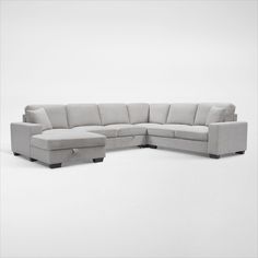 a large sectional couch sitting on top of a white floor next to a footstool