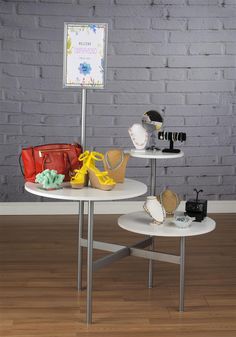 two tables with purses on them in front of a brick wall