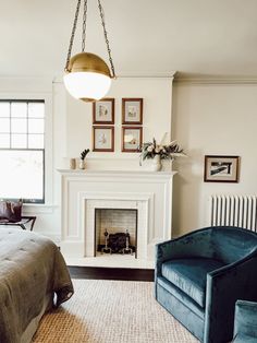 a bedroom with a bed, chair and fire place in front of a fireplace that has pictures on the wall above it