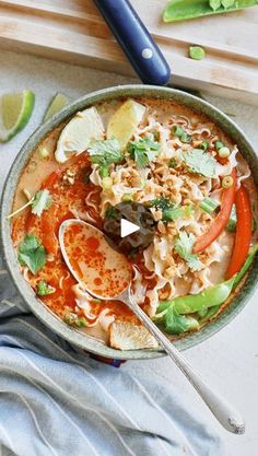 a bowl filled with noodles and vegetables on top of a cutting board