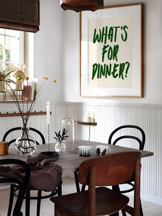 a dining room table with chairs and a poster on the wall above it that says what's for dinner?