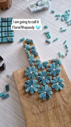 a wooden cutting board topped with blue flowers next to scissors and other crafting supplies