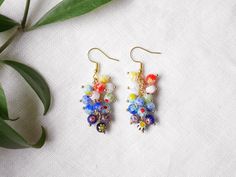 Millefiori dangle earrings are so cute and colorful! Packed with small (4 mm) multicolor millefiori glass beads, the earrings are perfect for summer and add color to any outfit. Gold-plated.  Height: 1.9 inches / 4,8 cm, including the earwire. Looking for a set? Here's a matching... necklace: https://www.etsy.com/listing/1270181471 ring: https://www.etsy.com/listing/1118874356 bracelet: https://www.etsy.com/listing/1256169342 ♥ Jewelry care ♥ It's important to keep your jewelry dry: Take it off before taking a shower, bath, swimming, or exercising. Always apply your makeup, perfume, and hairspray before putting on your jewelry.  Store your jewelry somewhere dry (not in the bathroom). See my whole jewelry collection: https://www.etsy.com/shop/Tazelry Multicolor Summer Flower Charm Earrings, Summer Multicolor Flower Charm Earrings, Multicolor Floral Print Flower Earrings, Summer Multicolor Earrings With Flower Charm, Elegant Multicolor Round Beads Flower Earrings, Bohemian Multicolor Floral Print Earrings, Multicolor Beaded Flower Earrings With Flower Charm, Multicolor Flower Shaped Beaded Earrings With Flower Charm, Multicolor Flower-shaped Earrings With Dangling Beads