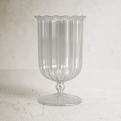 a clear glass vase sitting on top of a white tableclothed floor next to a wall