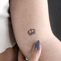 a woman's arm with a small crown tattoo on the left side of her body