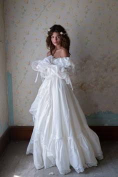 a woman in a white dress standing against a wall