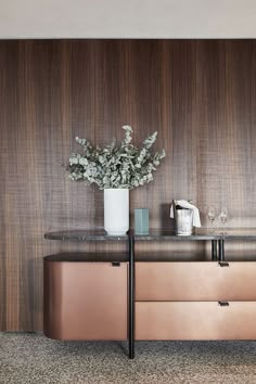 a vase filled with flowers sitting on top of a wooden dresser next to a wall