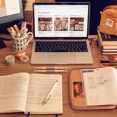 an open laptop computer sitting on top of a wooden desk next to books and pencils