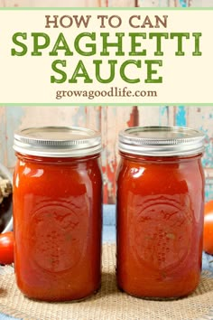 two jars filled with homemade spaghetti sauce sitting on top of a table next to tomatoes