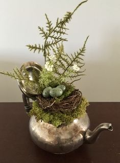 a metal teapot with moss and eggs in it