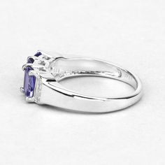 "Tanzanite Ring, Real 3-Stone Tanzanite and Diamond Sterling Silver Ring, Tanzanite Cushion Silver Ring, Bridesmaid Gift, December Birthstone .925 Sterling Silver Stone Details: Tanzanite Item Type: Ring Subcategory: Tanzanite Gross Wt: 2.83 Gemstone Wt: 1.59 ctw Diamond Wt: 0.04 ctw Total Stone Wt: 1.63 ctw Metal Stamp: 925 QJ™ IN Finish: Rhodium Plated Product Style: 3 Stone Ring Total Qty Of Stones: 11 Height: 25.18 MM Width: 16.21 MM Length: 6.43 MM Primary Stone Color: Violet Birthstone Mon Tanzanite Three-stone Ring For Anniversary, Silver Tanzanite Birthstone Ring, Tanzanite Three-stone Round Jewelry, Brilliant Cut Tanzanite Gemstones For Gift, Silver Tanzanite Multi-stone Rings, December Jewelry, Tanzanite Bracelet, 3 Stone Ring, Oval Stud Earrings