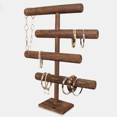 a wooden jewelry rack with rings and chains hanging from it's sides, on a white background