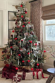 a decorated christmas tree in a living room with red and silver ornaments on the top