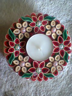 a candle is sitting on the floor next to a flower shaped plate with buttons and leaves