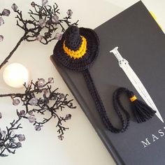 a crocheted hat sitting on top of a book next to a lit candle