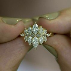 a woman's hand holding a ring with three diamonds on it and two fingers