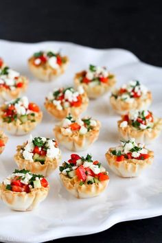 small appetizers on a white platter with cheese and tomatoes in the middle