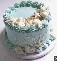 a blue and white cake with sea shells on it