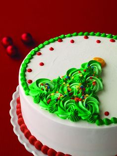 a white cake with green frosting and decorations on it's side, sitting on a red surface