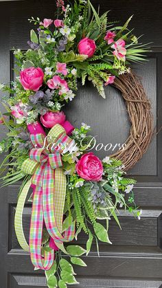 a wreath with pink flowers and greenery on the front door