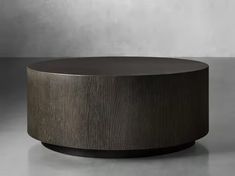 a round wooden table sitting on top of a gray floor