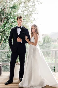 a bride and groom posing for a photo in front of a balcony with potted plants