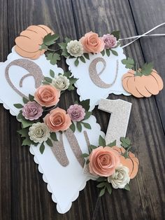 paper pumpkins and flowers are arranged on top of a white sign with the letter e