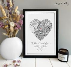 a black and white framed print with a heart shaped map in the center, next to some dried flowers