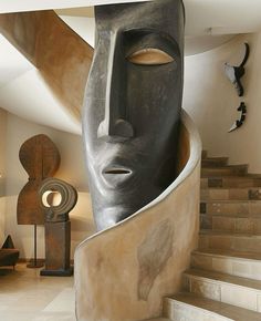 a large sculpture in the shape of a woman's head on top of some stairs