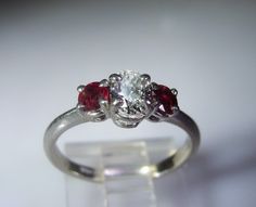 "This is a gorgeous Platinum Diamond and Ruby Ring from Circa 1960s. The center stone is genuine Oval Cut Diamond that is a \"VS\" Quality Diamond. The measurements are 5.5mm by 3.9mm making it just below a half a carat in size and an approximate size of .47 of a Carat. On each side of the center diamond are two lovely round cut genuine ruby gems. Each Ruby measures approximately 3.5mm in size which is approximately .30 in total carat weight (.15 each). This is a very pretty, petite ring with a Gia Certified Oval Ruby Ring For Wedding, Heirloom Oval Ruby Ring Gia Certified, Gia Certified Heirloom Oval Ruby Ring, Heirloom Oval Gia Certified Ruby Ring, Oval Three Stone Ruby Ring With Diamonds, Oval Ruby Ring With Three Diamonds, Oval Brilliant Cut Ruby Promise Ring, Classic White Oval Ruby Ring, Vvs Clarity Oval Ruby Ring For Wedding