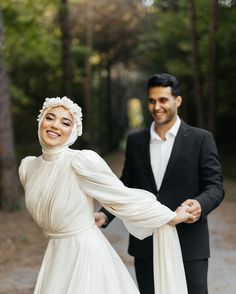 a man and woman dressed in wedding attire holding hands