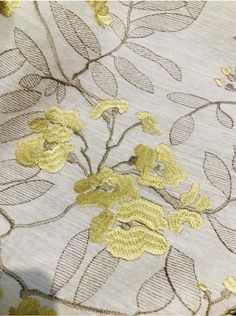 a close up view of a yellow flower on a white fabric with gold foiling