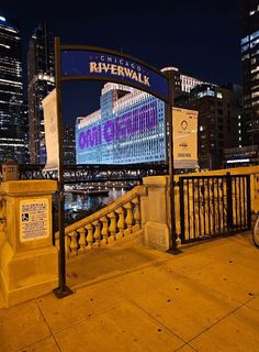 there is a sign that says riverwalk in front of the city skyline at night