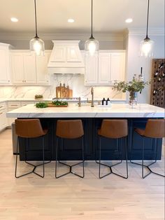 a kitchen with white cabinets and an island in the middle is surrounded by bar stools