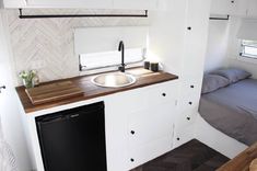 a small kitchenette with sink, dishwasher and bed in the back ground