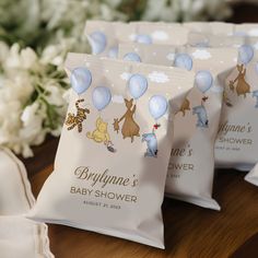 baby shower bags with winnie the pooh balloons on them and flowers in the background