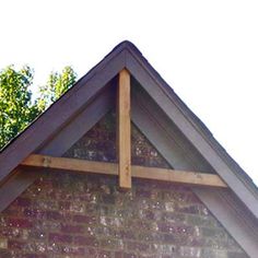 the top of a brick building with a cross on it's roof and trees in the background