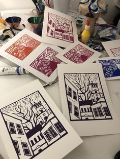 five paper cut art pieces on a table with paint and brushes next to them,