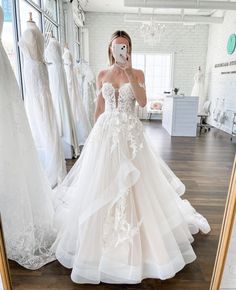 a woman in a wedding dress is taking a selfie with her cell phone while looking at herself in the mirror