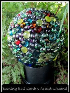 a ball made out of glass beads sitting on top of a metal stand in the grass