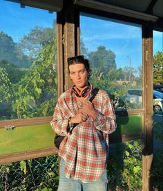 a man standing in front of a window with his hand on his chest and looking at the camera