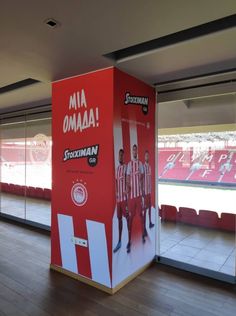 a red and white box in the middle of a wooden floor with two men standing next to it