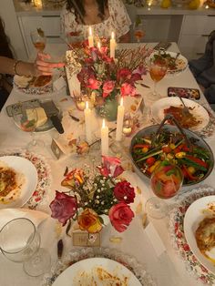 a woman sitting at a table with food and candles