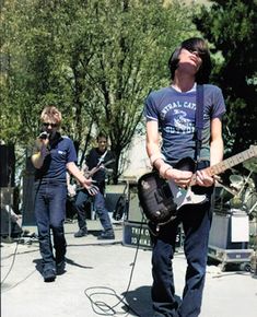 a group of people that are playing some music on the street and one man is holding an electric guitar