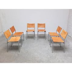 six chairs and one table are arranged in the shape of a circle on concrete floor