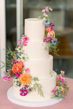 a three tiered white wedding cake decorated with flowers