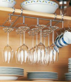 wine glasses and plates are hanging on the shelf